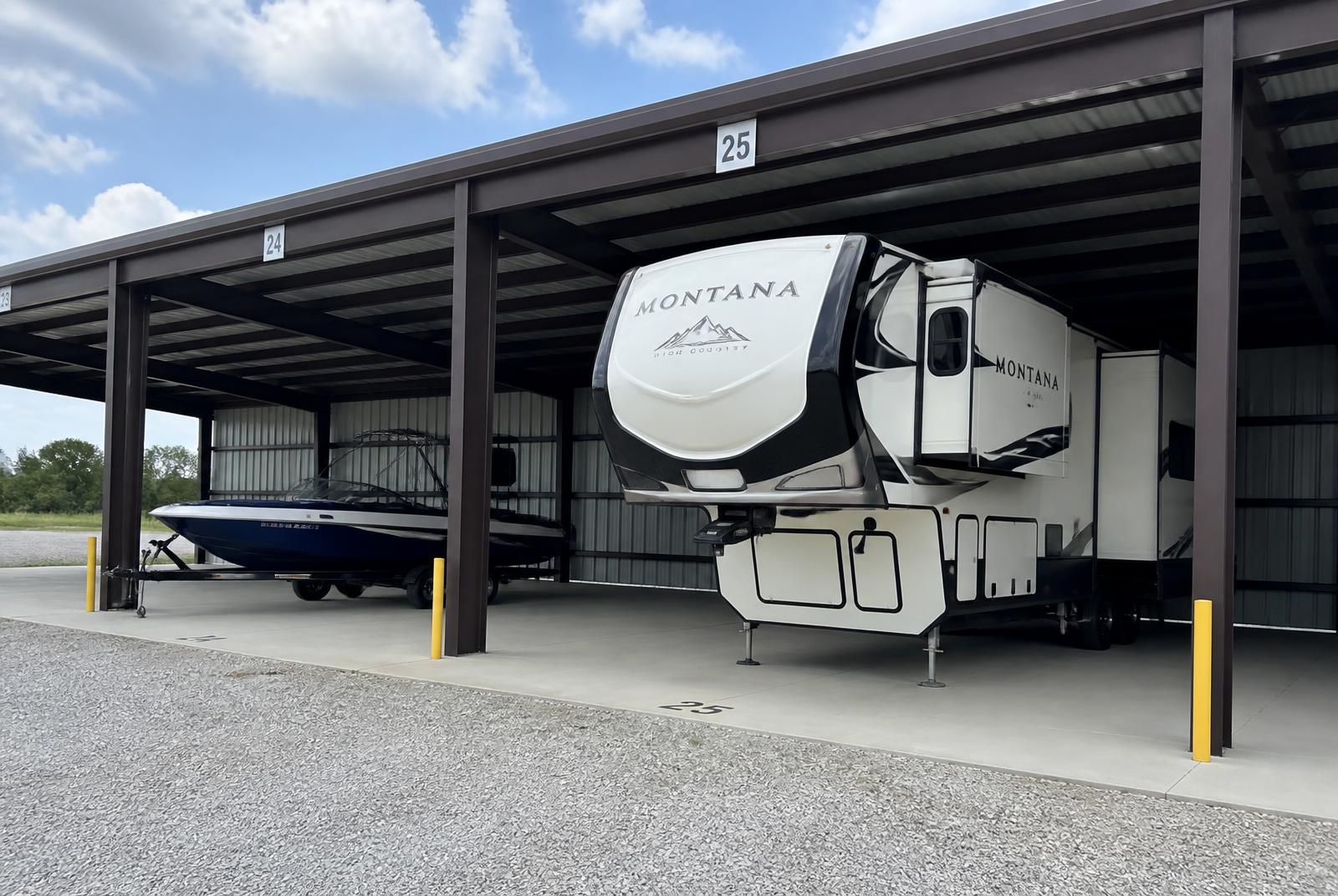 A wake boat on a trailer parked in a covered storage bay